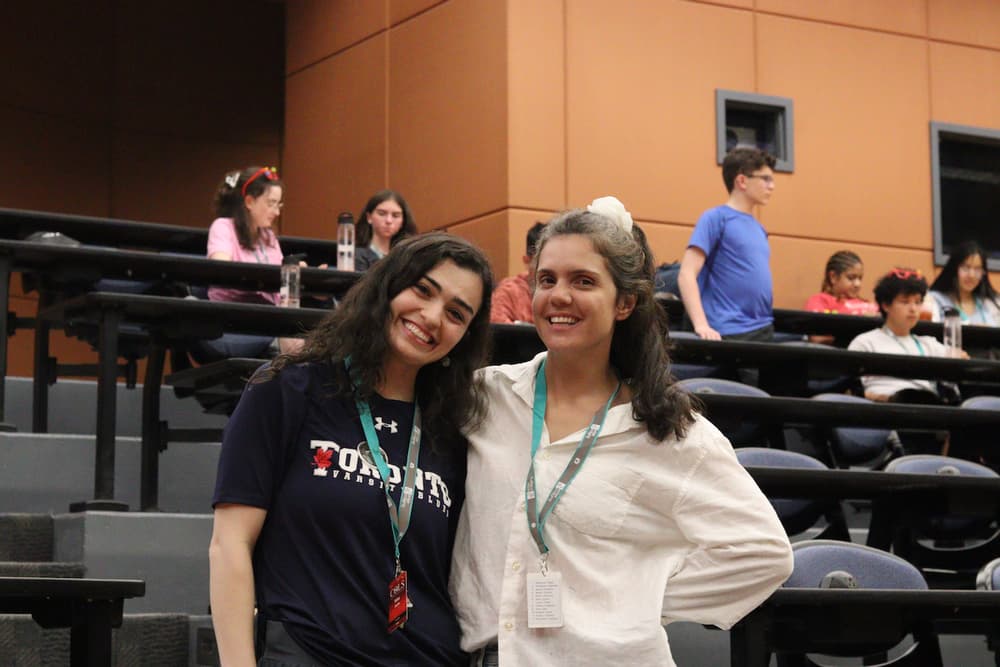 Two smiling COLS participants with their arms around each other in a lecture hall