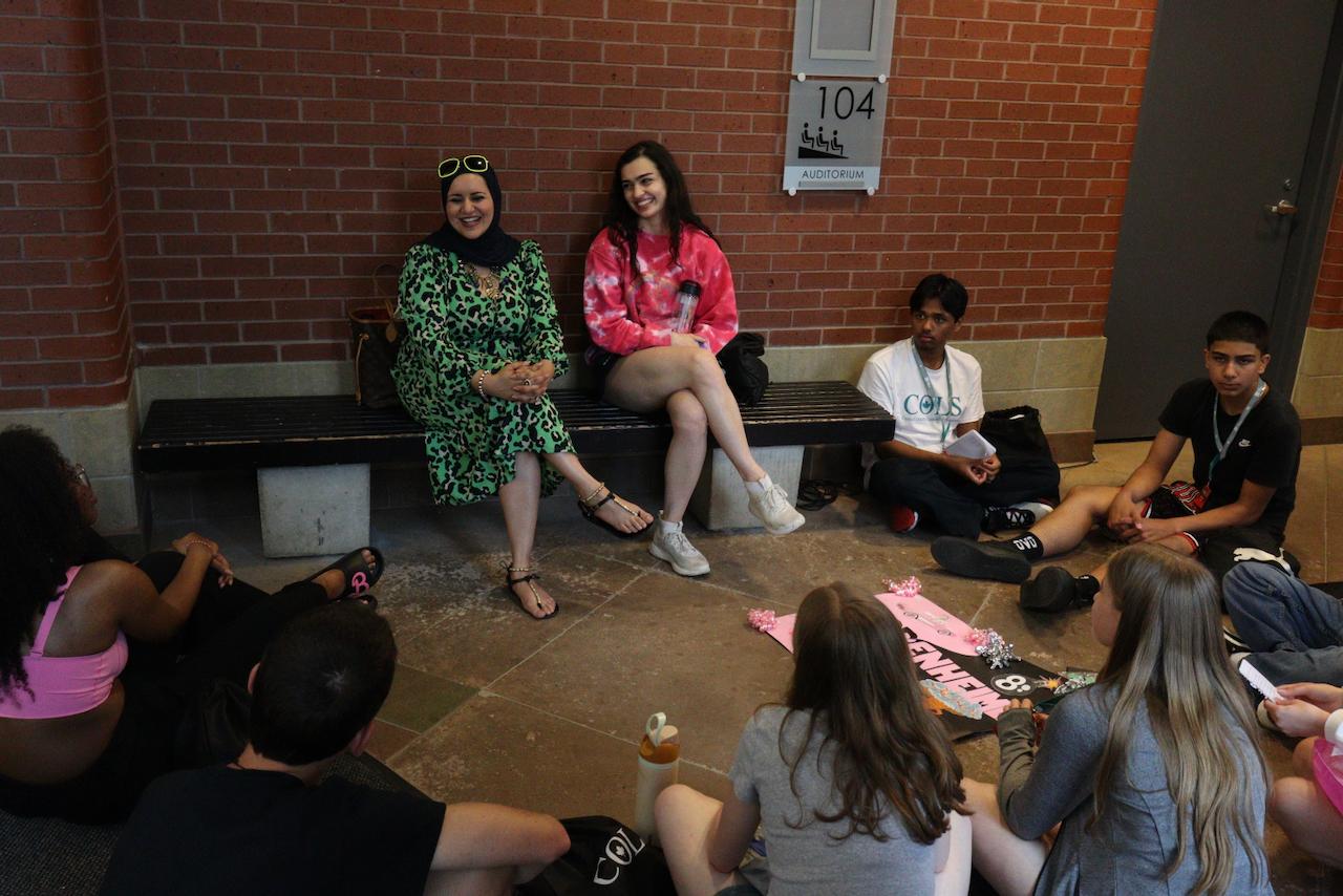A small group sitting in a circle on the floor, talking with a COLS leader