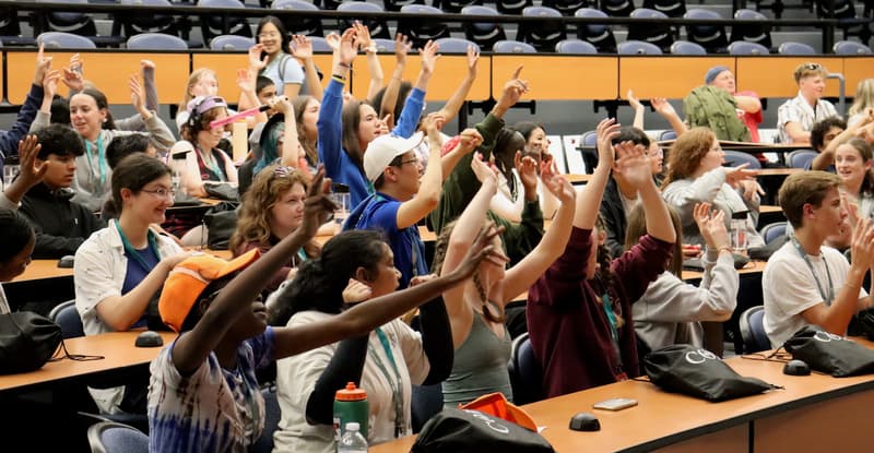 Ambassadors in a lecture hall raising their hands and cheering